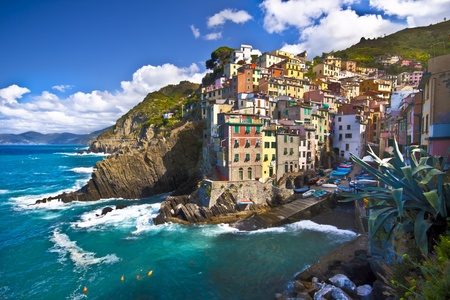 Riomaggiore fisherman village in a dramatic windy weather. Riomaggiore is one of five famous colorful villages of Cinque Terre in Italy, suspended between sea and land on sheer cliffs upon the  turquoise sea.の写真素材