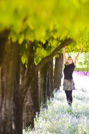 Young lady smiling with arms raised to the crown, enjoying the fresh air in green park.の写真素材