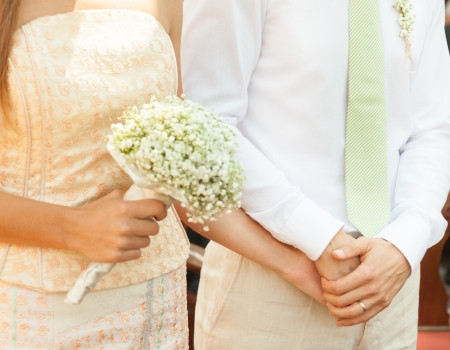 Close up of a bride and groom holding hands during wedding ceremony.の写真素材