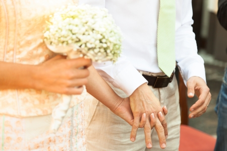 Close up of a bride and groom holding hands during wedding ceremony.の写真素材