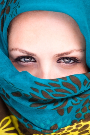 Beautiful Arab woman wearing blue scarf, stylish female close up face portrait, serious expression, stunning sensual beauty.の写真素材