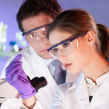 Attractive young scientist and her post doctoral supervisor looking at the microscope slide in the forensic laboratory.の写真素材
