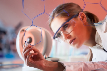 Portrait of a confident female health care professional in his working environment writing structural chemical formula on a glass board.の写真素材