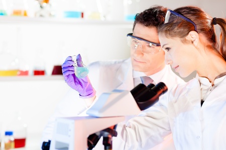 Chemical laboratory scene: attractive young student and her post doctoral supervisor scientist observing the green indicator solution color shift in glass flask.の写真素材