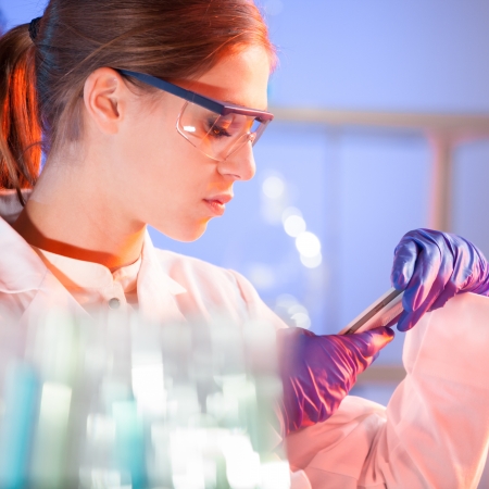 Laboratory scene: attractive young scientist checking the experiment protocol on a smarth phone application.の写真素材