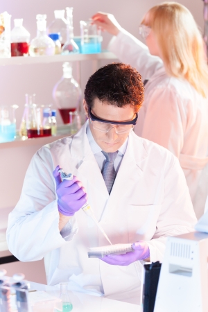 Focused life science professionals pipetting master mix solution into the PCR 96 well micro plate in the genetic lab.の写真素材