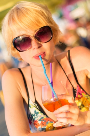 Cute young lady  drinking cocktail on the outdoor terrace on a lovely sunny  day.の写真素材