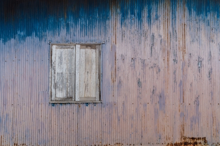 Old rusty house with closed wooden shutters; can be used as a graphical background の写真素材
