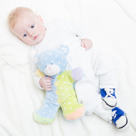 Cute blonde little baby boy with blue eyes with his favorite plush teddy bear and elephant.の写真素材