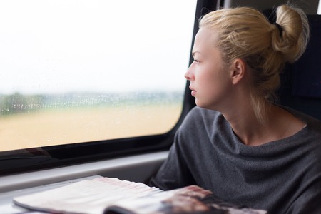Thoughtful blonde young lady traveling by train の写真素材