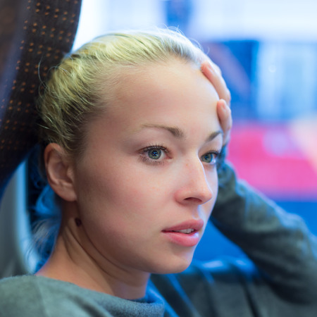 Thoughtful lady riding on a tram and looking out the window  