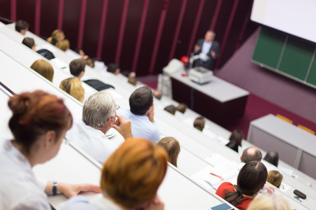 Lecturer at university. Healthcare expert giving a talk to medical faculty professors. Participants listening to lecture and making notes.の写真素材