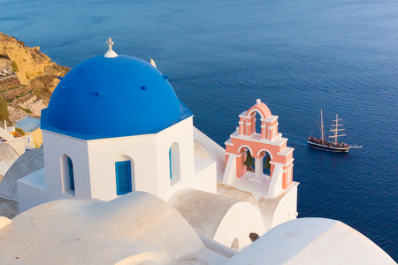 World famous traditional whitewashed chuches and houses of Oia village on Santorini island, Greece. Sunset light.の写真素材