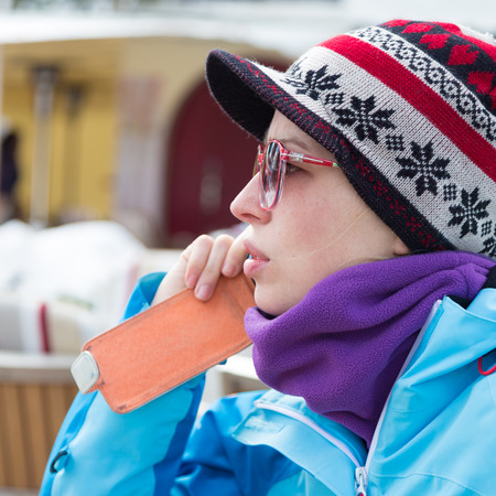 Woman on winter vacations in ski resort using smartphone.の写真素材