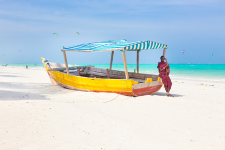 Maasai warrior lounging aroundon traditional colorful wooden boat on picture perfect tropical sandy...