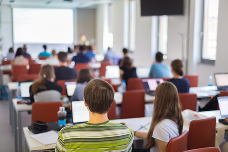 Workshop at university. Rear view of students sitting and listening in lecture hall doing practical...