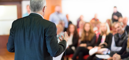 Speaker at Business Conference with Public Presentations. Audience at the conference hall. Entrepreneurship club. Rear view. Horisontal composition. Background blur.