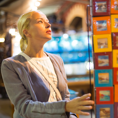 Beautiful casually dressed caucasian blond woman shopping for vacation souvenirs on crafts market in Chania, Crete, Greece.の写真素材