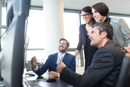 Successful business team looking at data on multiple computer screens in corporate office. Business, entrepreneurship and team work. Business success concept.の写真素材