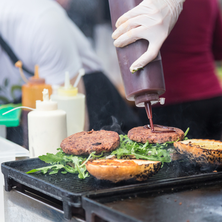 Chef making beef burgers outdoor on open kitchen international food festival event. Street food ready to serve on a food stall.の写真素材