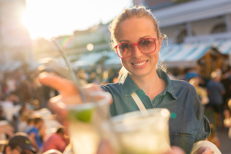 Beautiful young girl toasting outdoors on Open kitchen street food festival in Ljubljana, Slovenia....