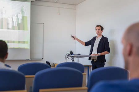 Relaxed confident smart student presenting his study work in front of whiteboard, defending his thesis. Doctoral thesis defense on faculty.の写真素材