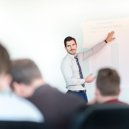 Business man making a presentation at office. Business executive delivering a presentation to his colleagues during meeting or in-house business training, explaining business plans to his employees.の写真素材