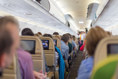 Interior of modern commercial airplane with passengers on their seats waiting to taik off.の写真素材