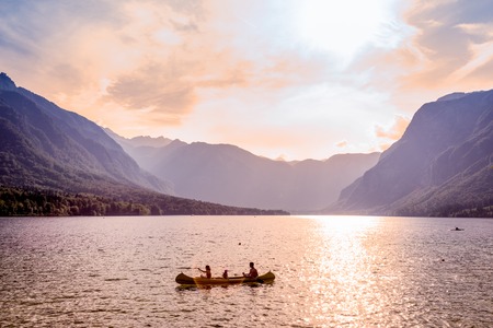Family rowing in canoe boat on beautiful lake Bohinj at sunset, located in the Bohinj valley of...