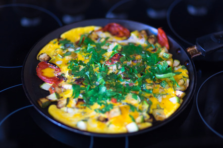 Omelet with vegetables in pan on elecric stove.の写真素材