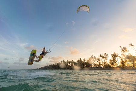 Kiteboarding. Fun in the ocean. Extreme Sport Kitesurfing. Kitesurfer jumping high in the air during dusk moonlight lit session.の写真素材
