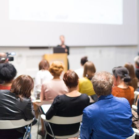 Business and entrepreneurship symposium. Speaker giving a talk at business meeting. Audience in the conference hall. Rear view of unrecognized participant in audience.の写真素材