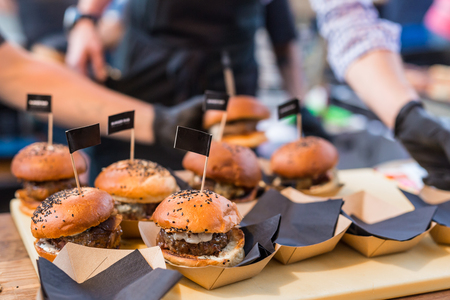 Chef making beef burgers outdoor on open kitchen international food festival event. Street food ready to serve on a food stall.の写真素材