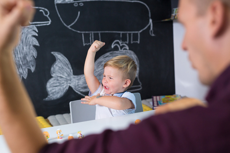 Cute little playfull toddler boy at child therapy session. Private one on one homeschooling with didactic aids.の写真素材