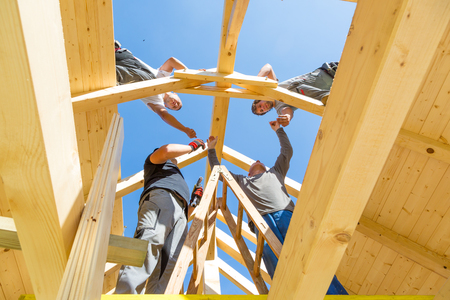 Roof builders mounting prefabricated wooden roof construction. Construction industry concept.の写真素材