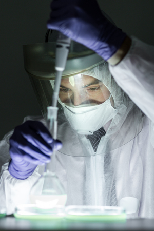 Life scientist researching in bio hazard laboratory. Focused life science professional working on experiment in high protection degree work laboratory. Healthcare and biotechnology.の写真素材