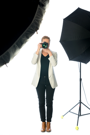 Woman photographer takeing images in photographic studio with dslr camera on white background.の写真素材