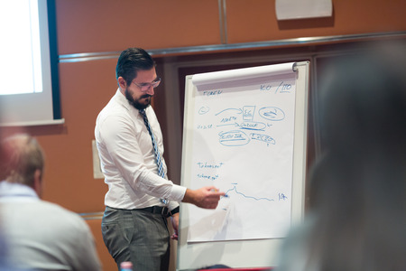 Skiled businessman presenting project to his work team at informal company business training...