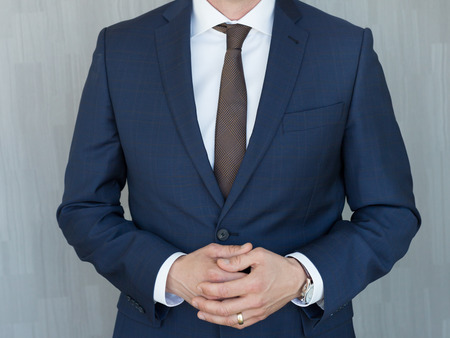 Torso of anonymous businessman standing with hands clenched in middle position wearing beautiful...