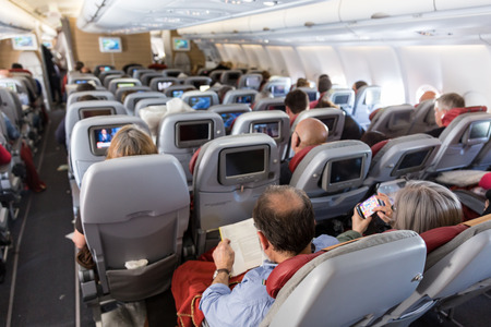 Interior of large commercial airplane with unrecognizable passengers on their seats during flight.
