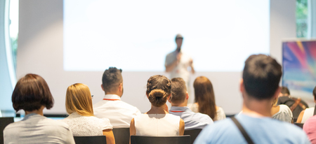 Speaker giving a talk in conference hall at business event. Audience at the conference hall. Business and Entrepreneurship concept. Focus on unrecognizable people in audience.の写真素材
