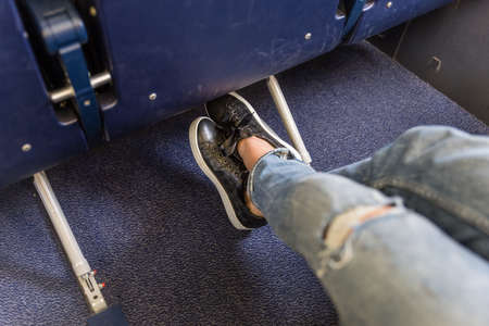 Female passenger stretching her legs on long commercial airplane flight. Exit seats with more leg space for more comfortable flight.の写真素材
