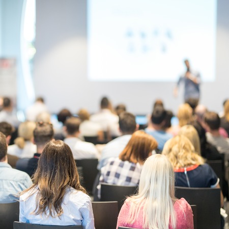 Speaker giving a talk in conference hall at business event. Audience at the conference hall. Business and Entrepreneurship concept. Focus on unrecognizable people in audience.の写真素材