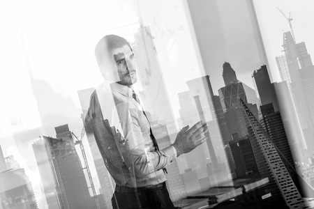 Business man making presentation in corporate office. Business executive delivering a presentation during business meeting against new york city manhattan buildings and skyscrapers window reflection.の写真素材