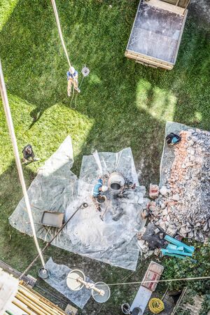 Top view of authentic builder men working with shovel during concrete cement solution mortar preparation in mixer at construction site.の写真素材