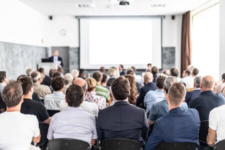 Speaker giving a talk in conference hall at business event. Audience at the conference hall. Business and Entrepreneurship concept. Focus on unrecognizable people in audience.の写真素材