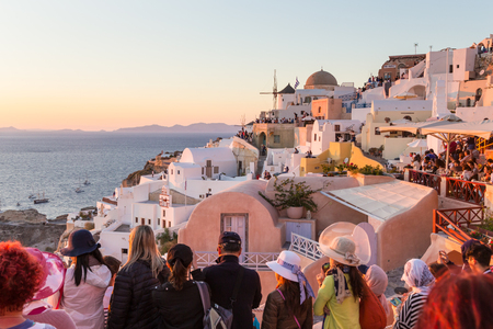 Oia, Santorini, Greece - Oct 10, 2017: Crowds of international tourists watching and taking travel photos of sunset on Santorini island on 11th of October, 2017 on Santorini, Greece.のeditorial素材