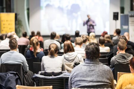 Speaker giving a talk in conference hall at business event. Audience at the conference hall. Business and Entrepreneurship concept. Focus on unrecognizable people in audience.の写真素材