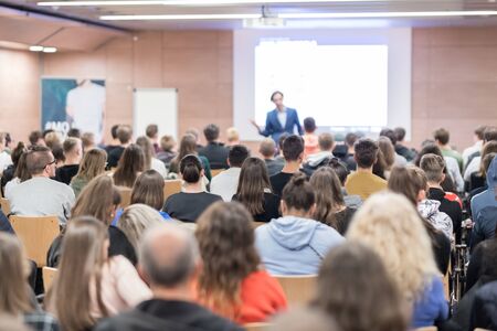 Speaker giving a talk in conference hall at business event. Audience at the conference hall. Business and Entrepreneurship concept. Focus on unrecognizable people in audience.の写真素材