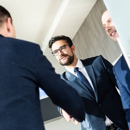 Group of confident business people greeting with a handshake at business meeting in modern office. Closing the deal agreement by shaking hands. Business and entrepreneurship success concept.の写真素材